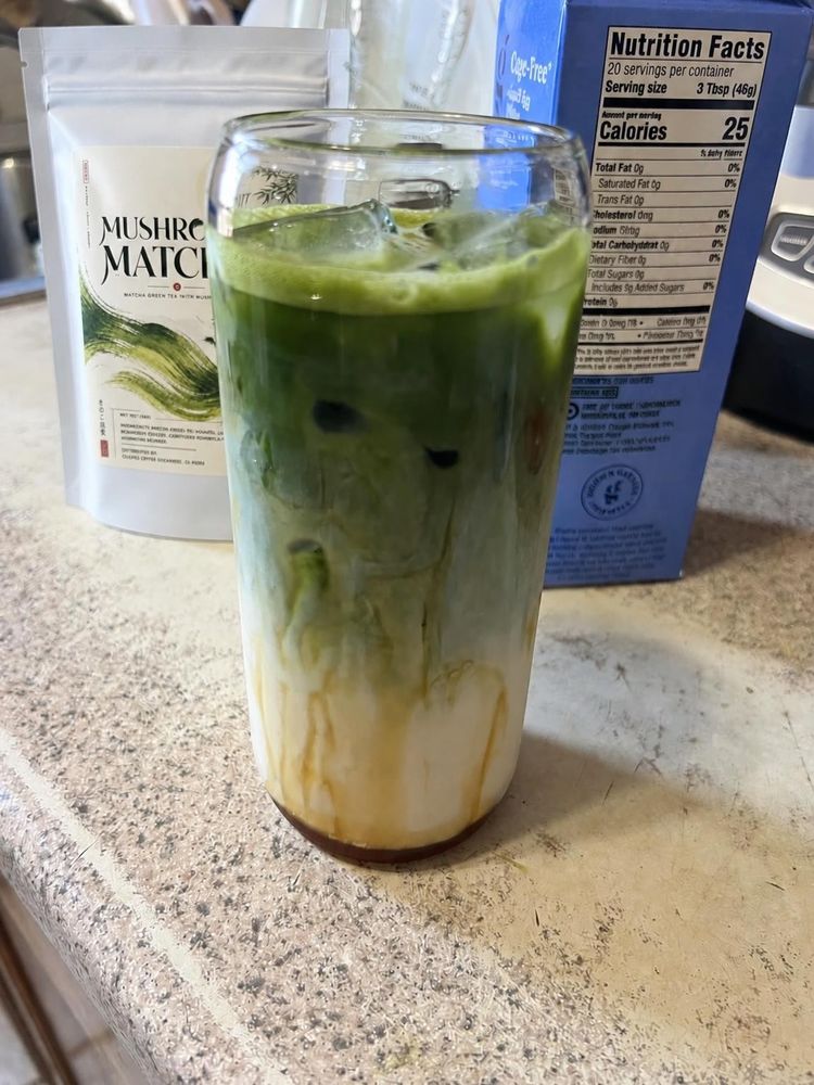Customer sipping an iced mushroom matcha latte beside the bag